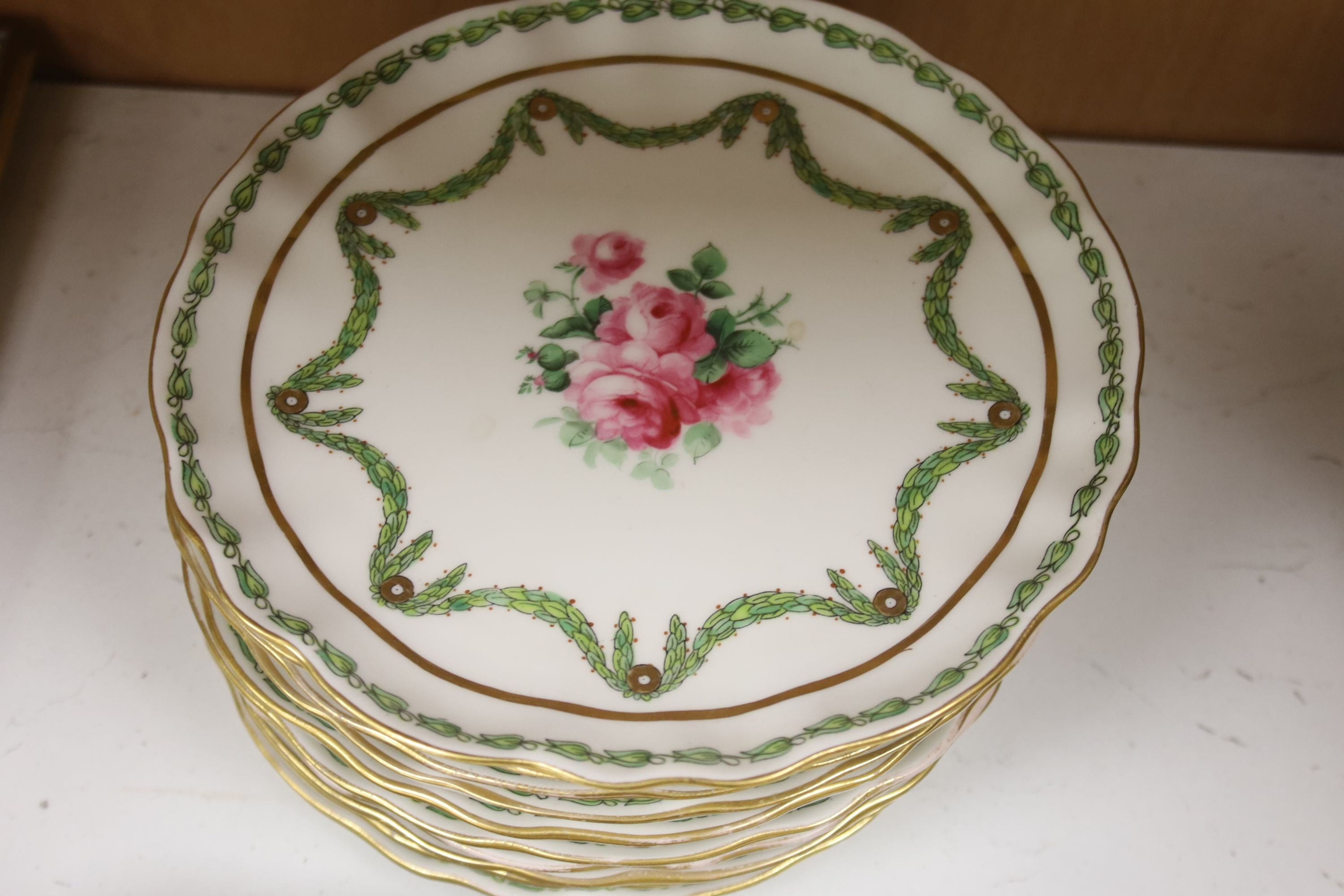 A quantity of 19th century hand painted floral plates, decorated with roses set within trailing garlands, marked T. Goode & Co, London